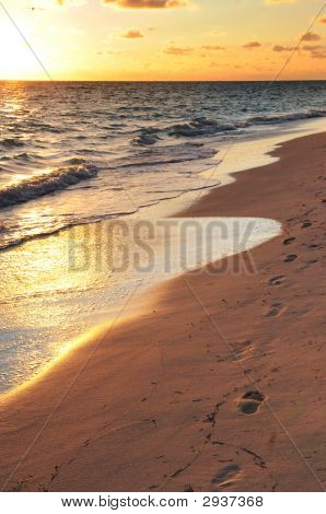 Empreintes de pas sur la plage de sable au lever du soleil