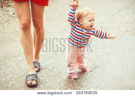 The Child Learns To Walk In The Park Barefoot On The Grass