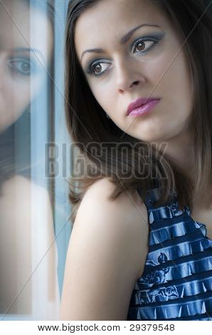 窓から見ている美しい若い女性の肖像画。