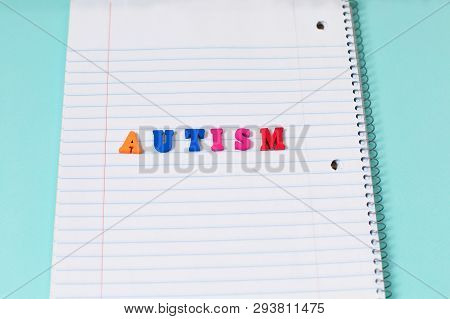 Autism Colorful Word From Color Wooden Letters On Notebook Page. Concept Image. Top View. Copy Space