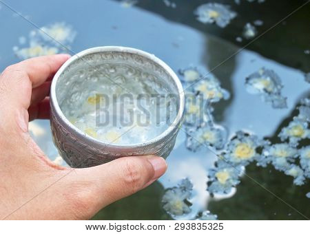 Buddhist Hand Holding A Small Bowls With Holy Water Or Blessed Water, Used To Drink, Cleaning The Bo