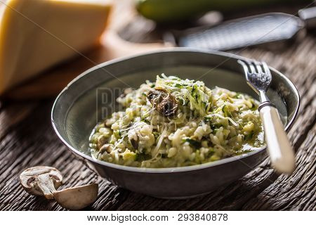 Italian Risotto Zucchini Mushrooms And Parmesan In Dark Plate.