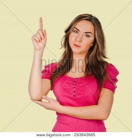 Young Woman Pointing Finger. Isolated On Background Cream Shade Yellow . Point Towards