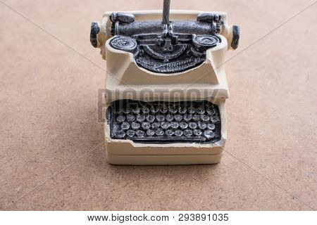 Retro Syled Tiny Typewriter Model On A Brown Background