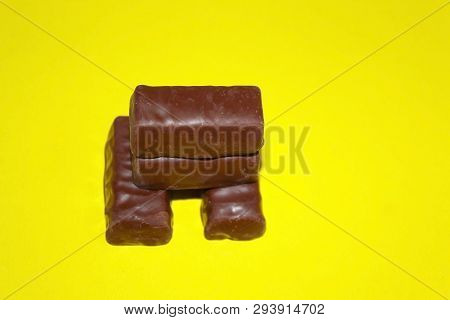 Four Chocolates Lie On A Yellow Background On Each Other