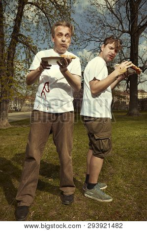Men In Street Park Eating Langos With Garlic, Ketchup And Cheese