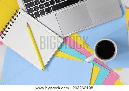 Flat Lay Photo Of Creative Workspace. Top View Of A Desk With Multicoloured Pastel Paper, Coffee Cup