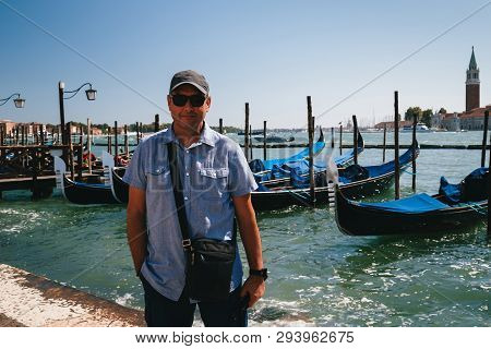 A Man Tourist Standing In Front Of The Gondolas At Traghetto Molo Near To The San Marco Square In Ve