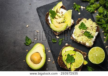 Sandwiches With Avocado And Cream Cheese With Grain Bread And Seeds. Black Slate Background, Top Vie