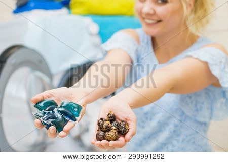 Woman Comparing Washing Laundry Nuts And Chemicals Detergent Blue Pods. Alternative Household Duties