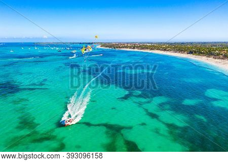 Tourists Parasailing Near Bavaro Beach, Punta Cana In Dominican Republic. Aerial View Of Tropical Re