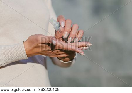 Hand Disinfection With Antiseptic. Against The Background Of A Gray Concrete Wall.