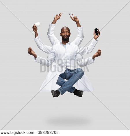Handsome African Doctor, Multi-armed Man Levitating Isolated On Grey Studio Background With Equipmen