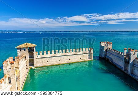 Sirmione, Italy, September 11, 2019: Small Fortified Harbor With Turquoise Water, Scaligero Castle C