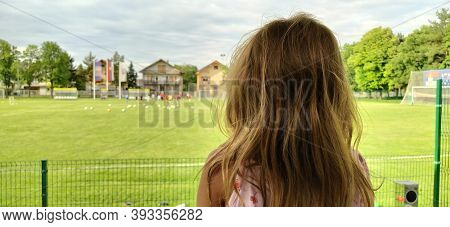Sremska Mitrovica, Serbia, August 1, 2020. A Girl Sits With Her Back To The Camera And Watches A Foo