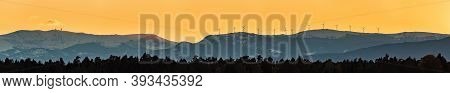 Styrian Alps Covered With Snow In Orange Light Of Sunset. View At Mountain Chain Of Lavanttaler Alps