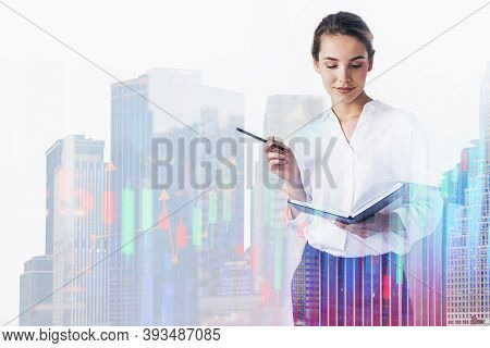 Young Businesswoman With Planner And Pen Working In Blurry City With Double Exposure Of Financial Gr
