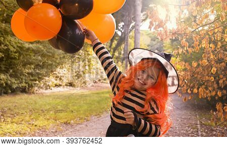 Halloween Party. Cild In A Carnival Costume On Halloween With Large Colored Balloons. Little Girl In