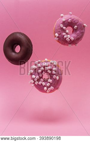 Close-up Of Three Donuts, Two Roses And One Chocolate, Levitating On A Pink Background. Vertical Pho