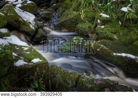 Water Flowing Through Moss Covered Rocks And Snow, Glencree, Ireland
