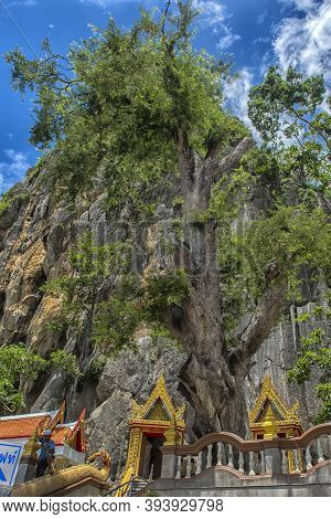 Thailand, Phetchaburi 19.07.2019 View Of Wat Tham Khao Yoi Cave, Buddhist Temple With Green Tree And