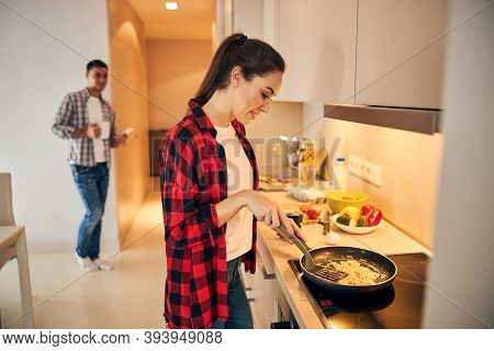 Pleased Female Making An Omelet On The Induction Cooktop