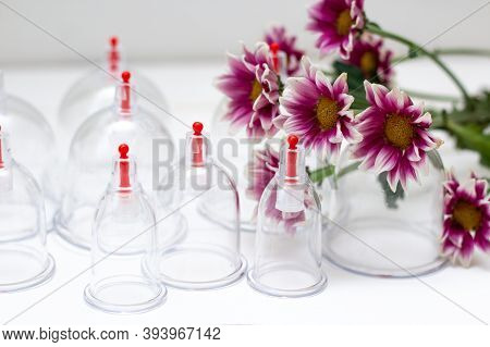 Jars For Hijama On A White Wooden Background And Pink Harezantems. Bloodletting. Sunnah Treatment. I