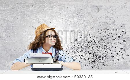 Young funny woman in glasses using typewriter