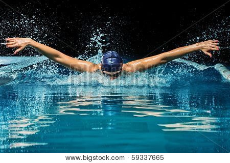 Young woman in blue cap and swimming suit in pool