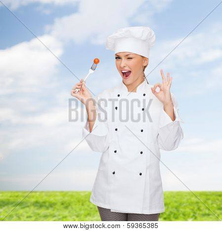 cooking and food concept - smiling female chef, cook or baker with fork and tomato showing ok sign