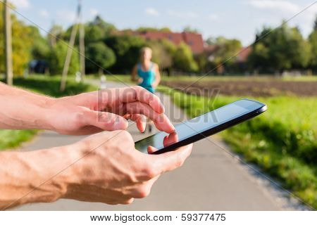 woman doing jogging or outdoor running sport for fitness on rural street, the trainer timing her with an app on tablet computer
