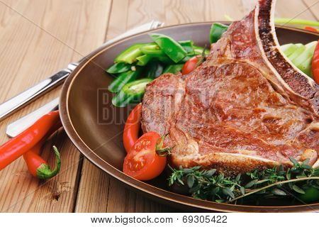 savory : grilled spare rib on dark dish with thyme pepper and tomato on wooden table