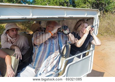 YALA NATIONAL PARK, SRI LANKA - MARCH 4, 2014: Tourists looking through binoculars during safari tour in the Yala park. Yala is the second largest national park in Sri Lanka.