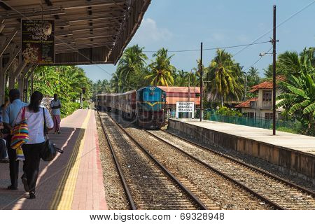 HIKKADUWA, SRI LANKA - MARCH 12, 2014: Train approaching Hikkaduwa train station. Trains are very cheap and poorly maintained but it's the best option to witness a bit of everyday local life.