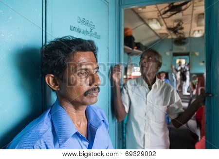 HIKKADUWA, SRI LANKA - MARCH 12, 2014: Two local men standing in train. Trains are very cheap and poorly maintained but it's the best option to witness a bit of everyday local life.