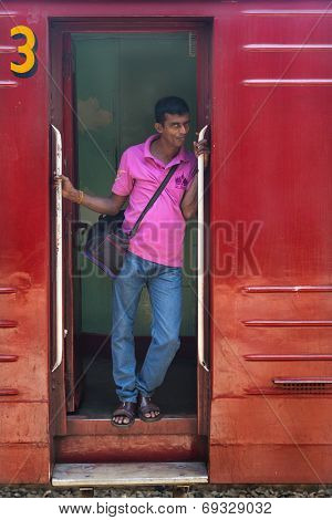 HIKKADUWA, SRI LANKA - MARCH 12, 2014: Local man standing at wagon entrance. Trains are very cheap and poorly maintained but it's the best option to witness a bit of everyday local life.