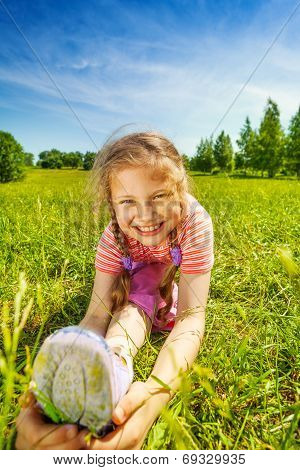 Smiling girl making leg-split on grass in summer
