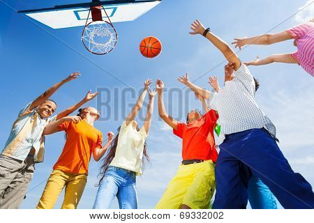 Children playing basketball with a ball up in sky