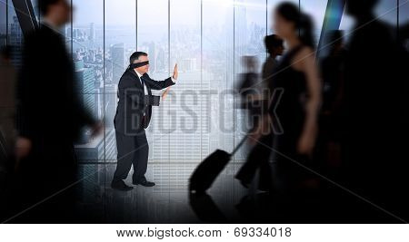 Mature businessman in a blindfold against room with large window looking on city