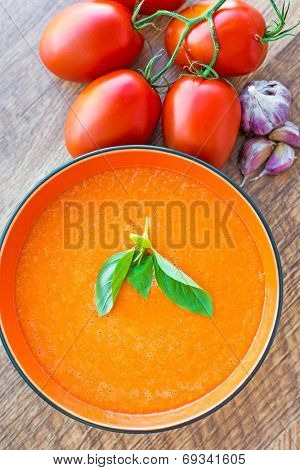 A bowl of tomato soup gaspacho with basil, tomatoes and garlic