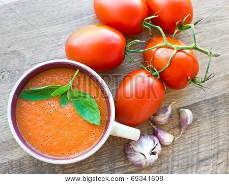 Bowl of tasty tomato soup gaspacho with basil, tomatoes and garlic