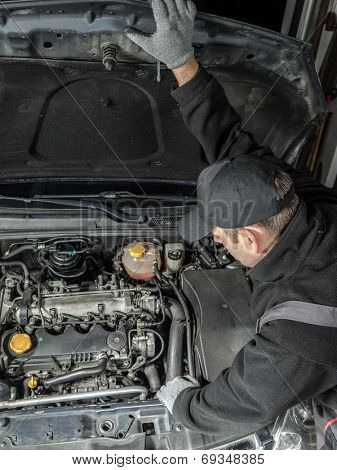 Auto mechanic inspecting car engine compartment