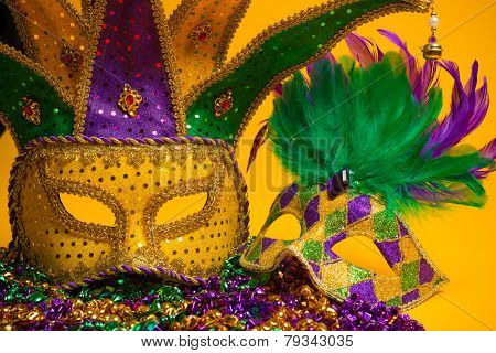 A festive, colorful group of mardi gras or carnivale mask on a yellow background.  Venetian masks.