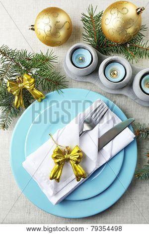 Christmas table setting in blue, golden and whitec olors on grey tablecloth background