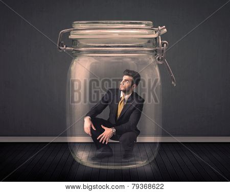 Businessman trapped into a glass jar concept on background
