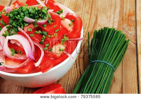 healthy food : fresh tomato salad in white bowl with bunch of chives and raw tomatoes on twig , onion,  over wooden table