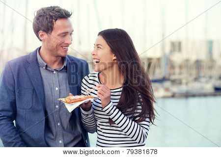 Dating couple tourists eating waffles on date enjoying food snack. Romantic man and woman laughing having fun outdoors. Multiracial couple, Young Caucasian man and Asian woman.