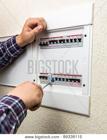 Closeup Of Young Handyman Fixing Fuseboard With Screwdriver