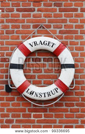 Old lifebuoy hanging on a brick wall in Lokken, Denmark