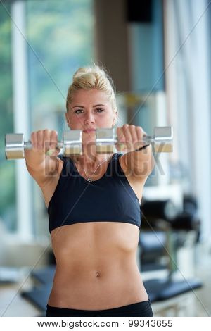 Gorgeou woman girl lifting some weights and working on her biceps in a gym